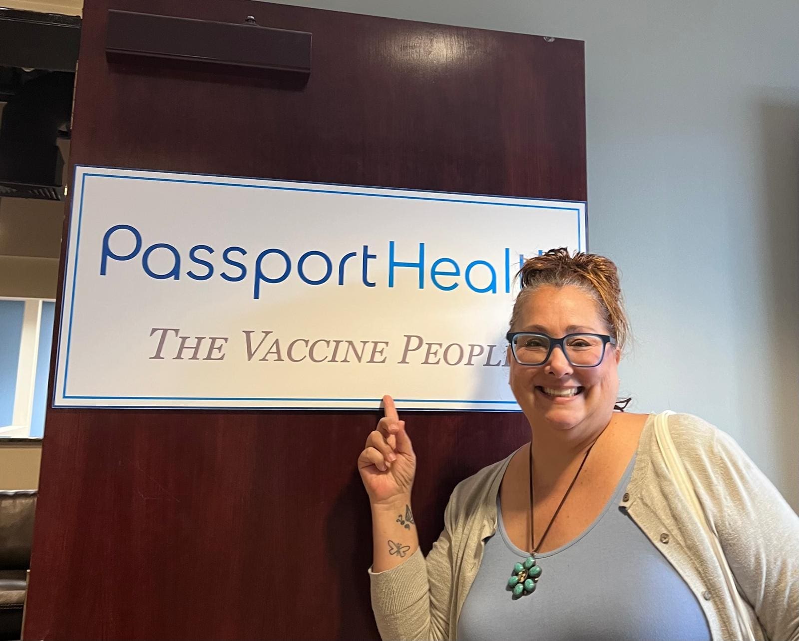 Kimberly Lorah standing beside a PassportHealth sign for The Vaccine Program while attending an Africa travel health presentation.